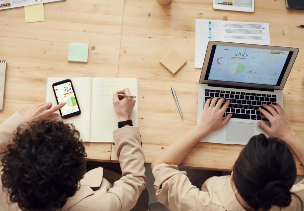 Overhead shot of two colleagues collaborating with devices and notes in a business meeting.
