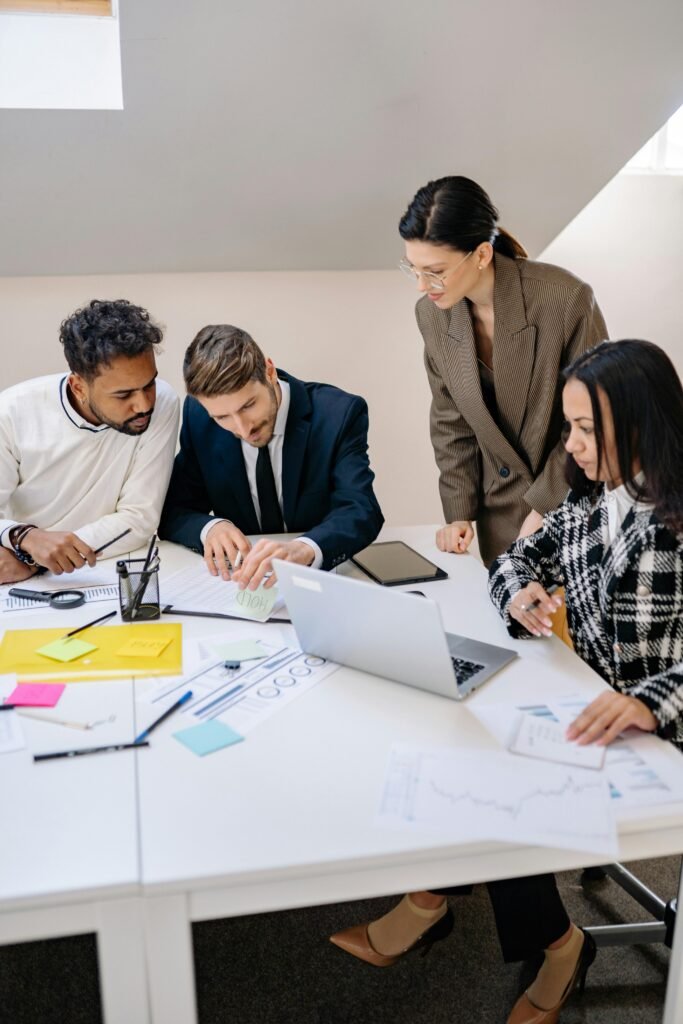 Business team brainstorming ideas at a workspace, using a laptop for planning.